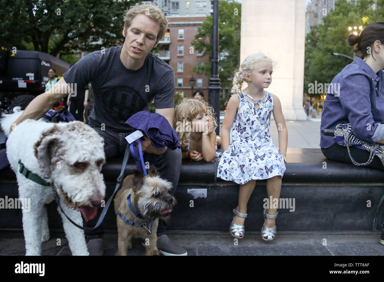 father, daughters and dogs sitting on bench in new york city Stock Photo