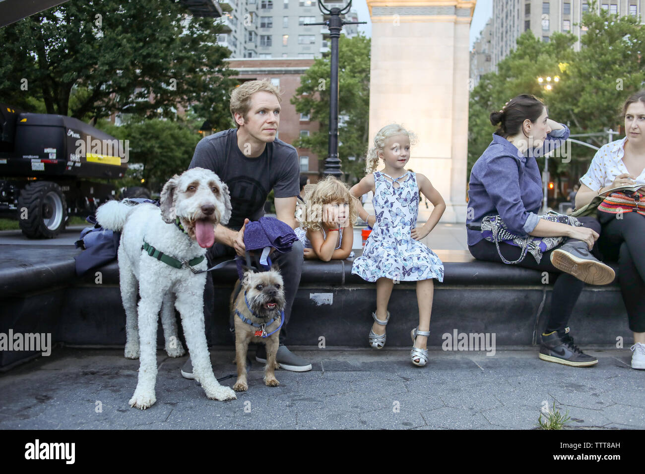 father and daughters with dogs sitting on bench in washington sq park Stock Photo
