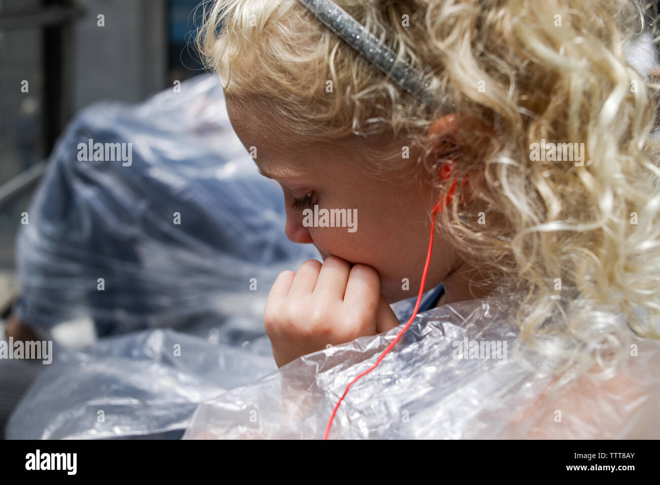 girl listening to headphones in poncho on sightseeing bus Stock Photo