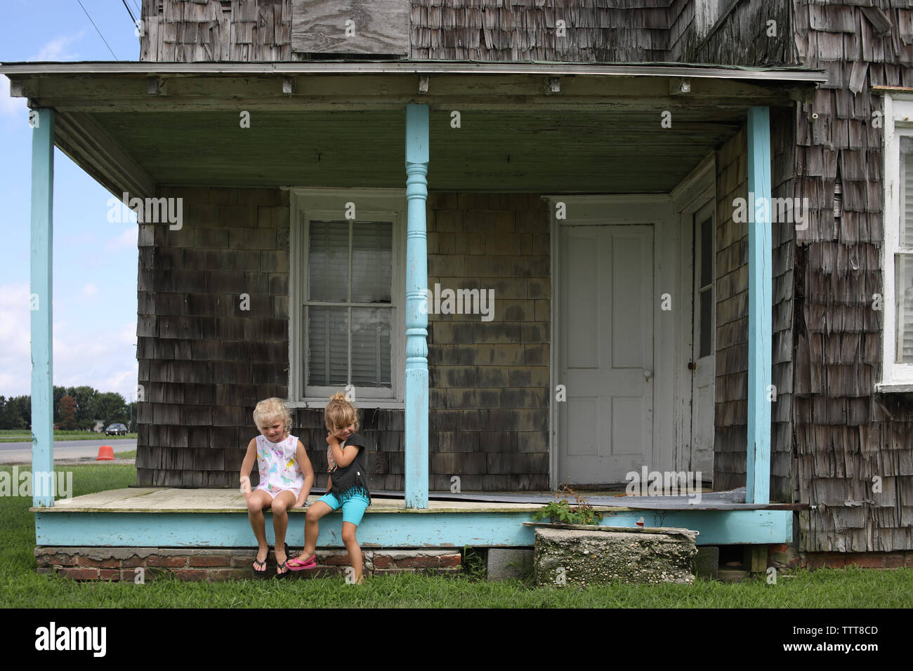 sisters sitting on front porch of old home Stock Photo Alamy