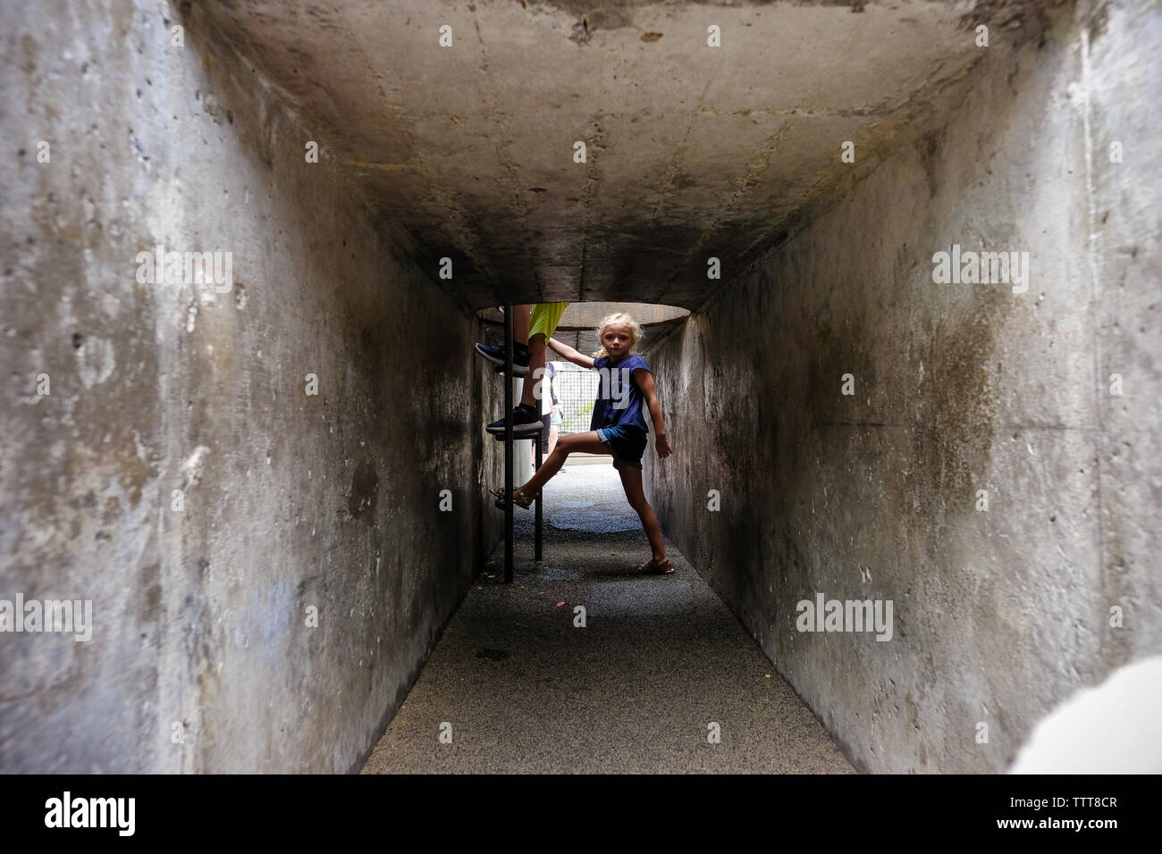 girl in tunnel waiting to climb stairs Stock Photo