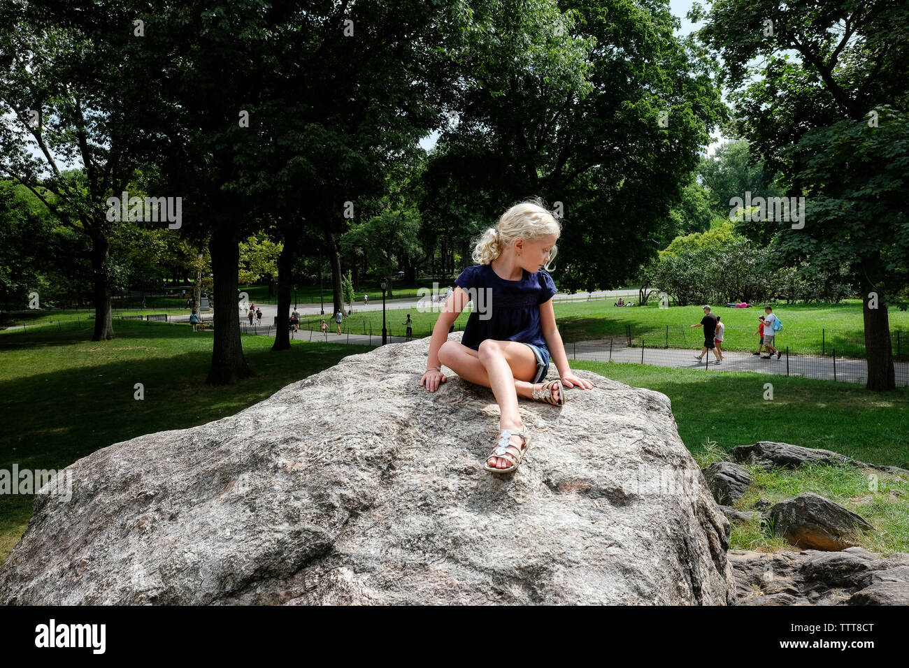 young girl sitting on top of rocks at central park in NYC in summer Stock Photo