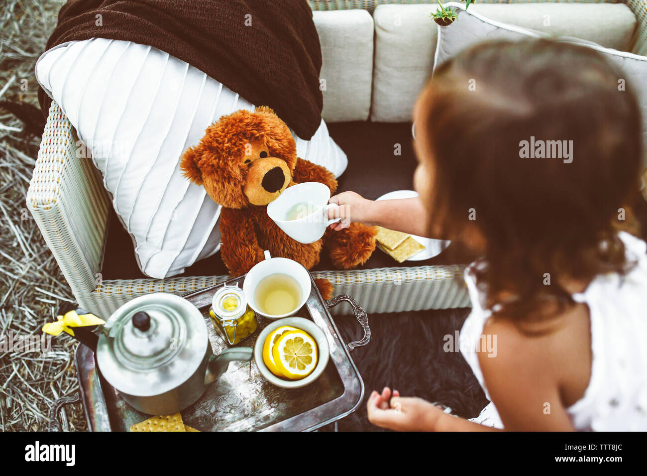 High angle view of girl feeding tea to teddy bear Stock Photo - Alamy