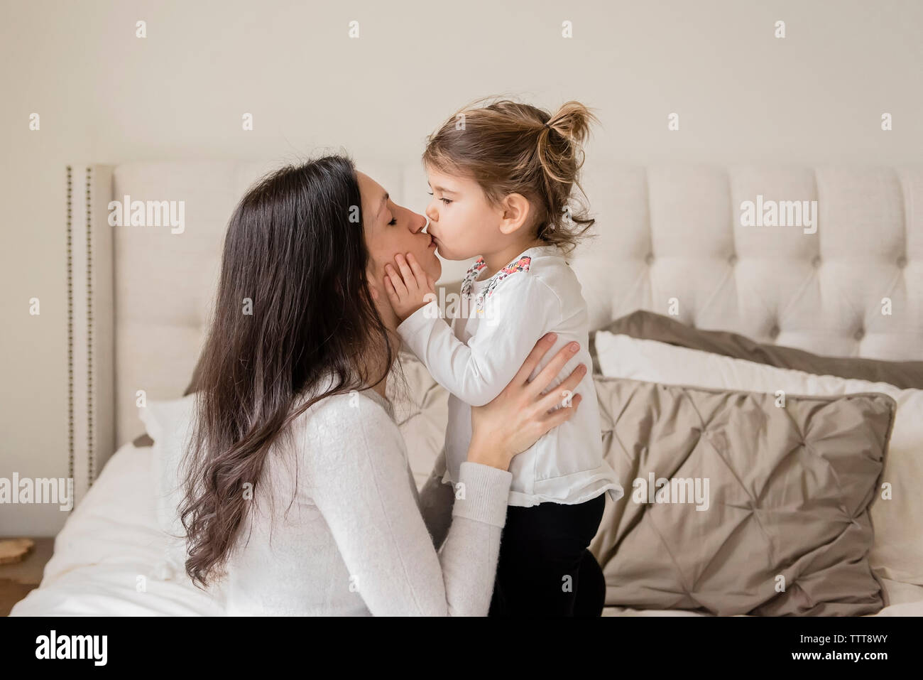 Girl kissing mother on bed hi-res stock photography and images - Alamy