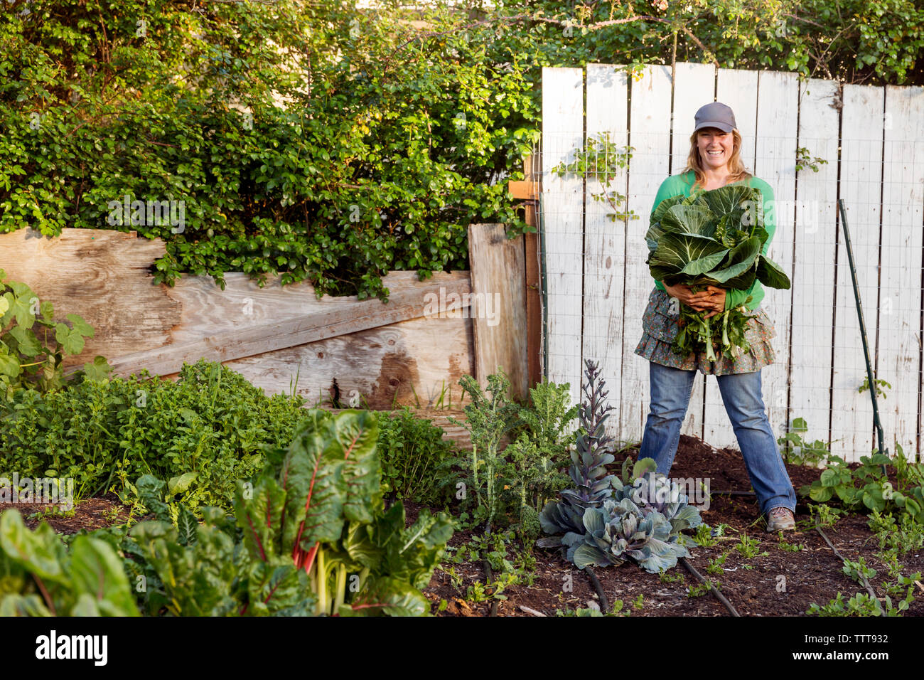 Portrait of woman farmer smiling holding freshly picked vegetables on farm Stock Photo