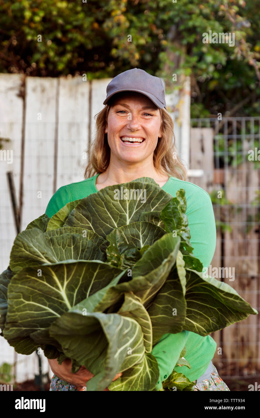 Portrait of woman farmer smiling holding freshly picked vegetables on farm Stock Photo