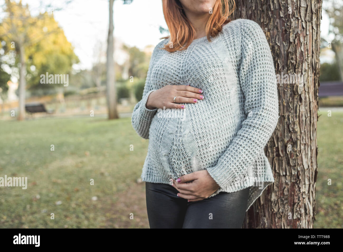 Young pregnant woman holding her belly at the park Stock Photo