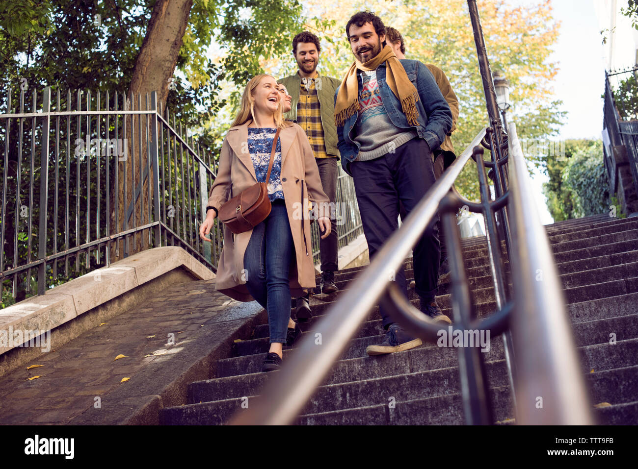 Low angle view of cheerful friends moving down steps outdoors Stock Photo