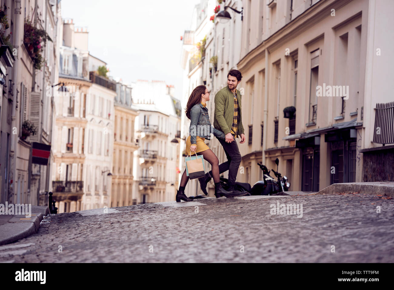 Young couple talking while crossing street in city Stock Photo