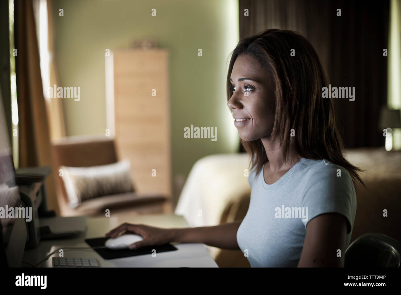 Smiling woman using computer in room at home Stock Photo