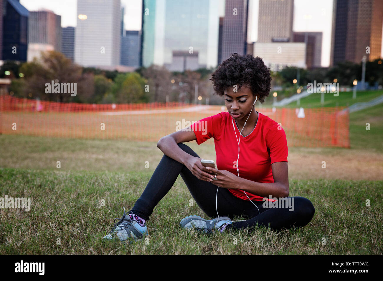 Woman listening to music while using phone at park Stock Photo