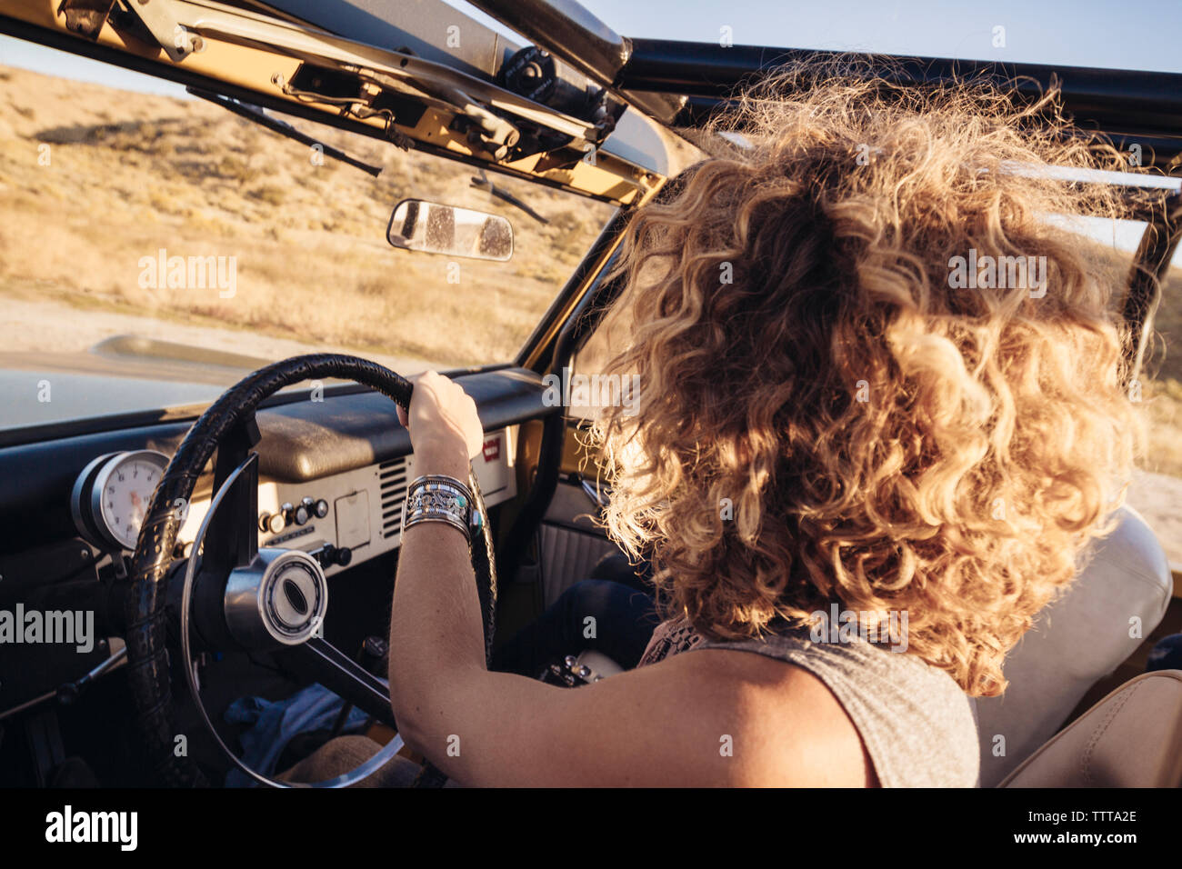 Side view of woman with curly hair driving off-road vehicle Stock Photo