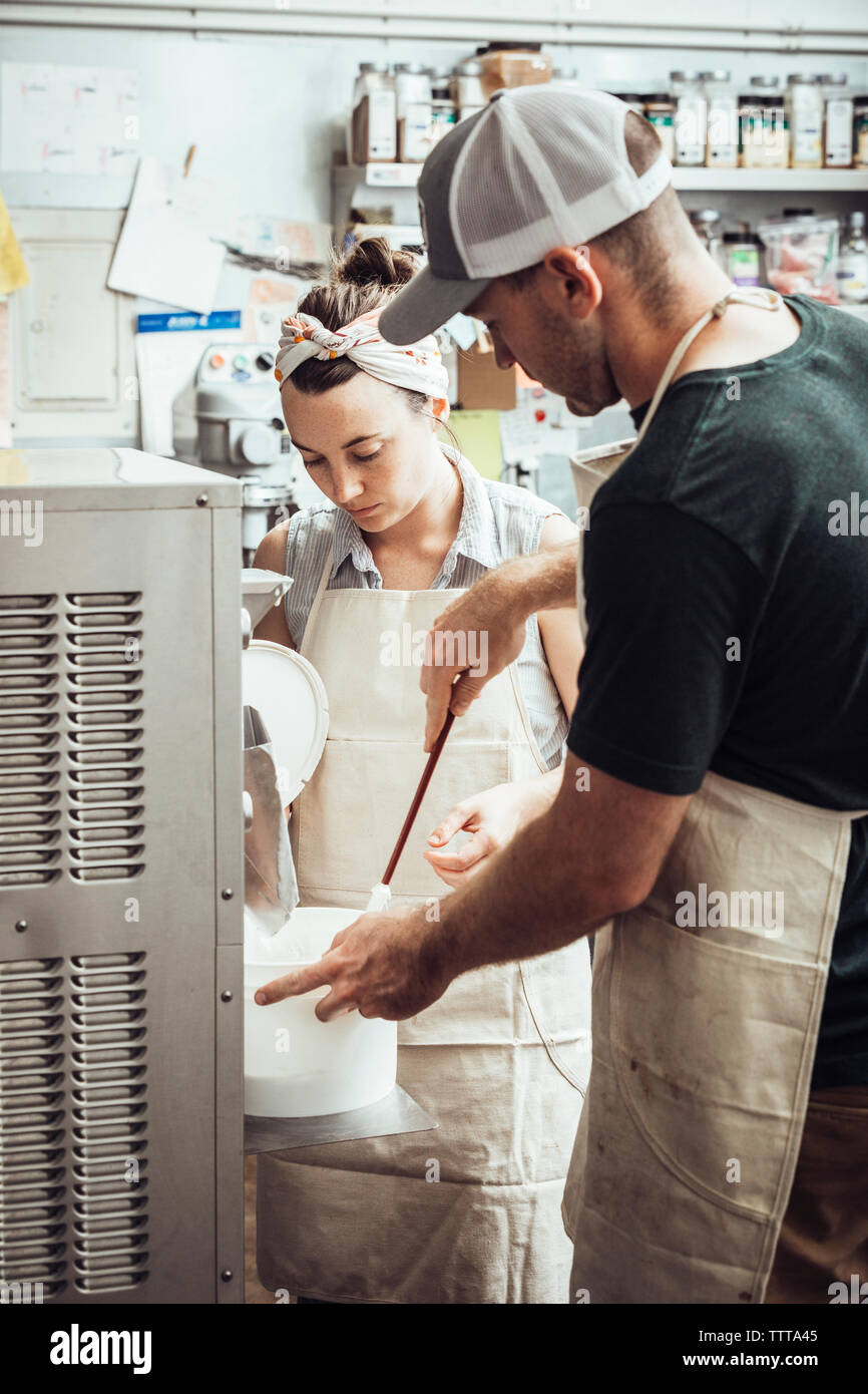 Colleagues using machinery while making ice cream at commercial kitchen Stock Photo