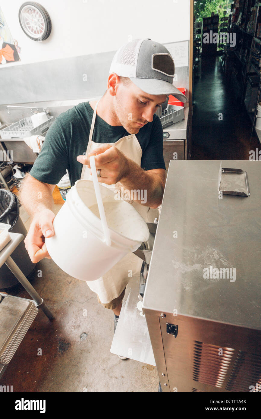 Man pouring ingredients in ice cream maker at commercial kitchen Stock Photo