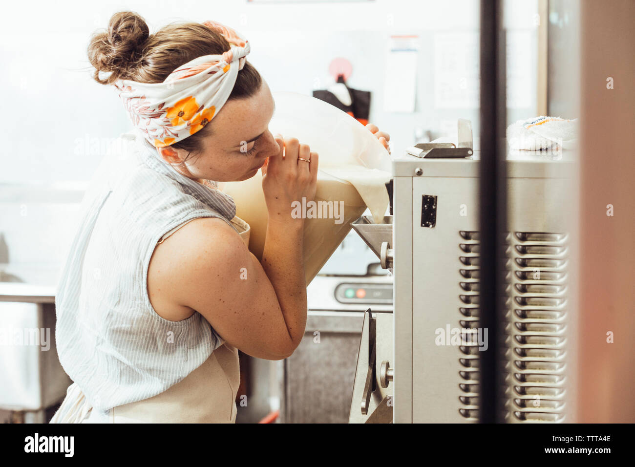 Woman pouring ingredients in ice cream maker at commercial kitchen Stock Photo