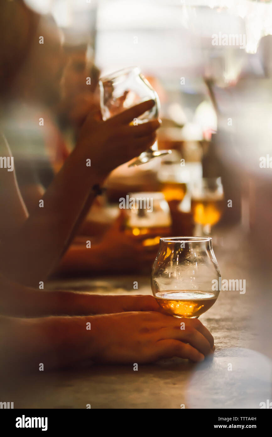 Friends holding beer glasses while sitting at bar Stock Photo