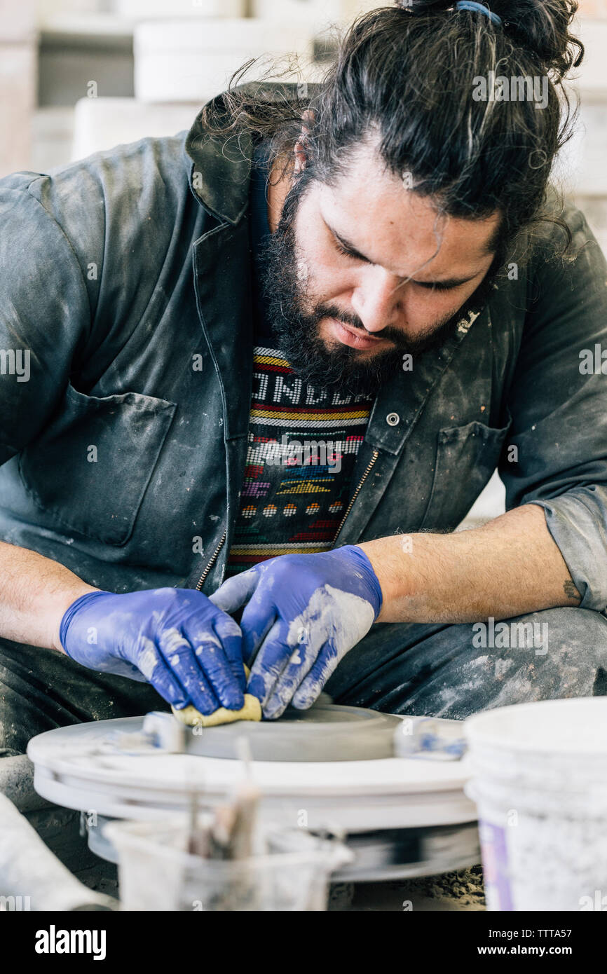 Craftsman cleaning pottery wheel while working in art studio Stock