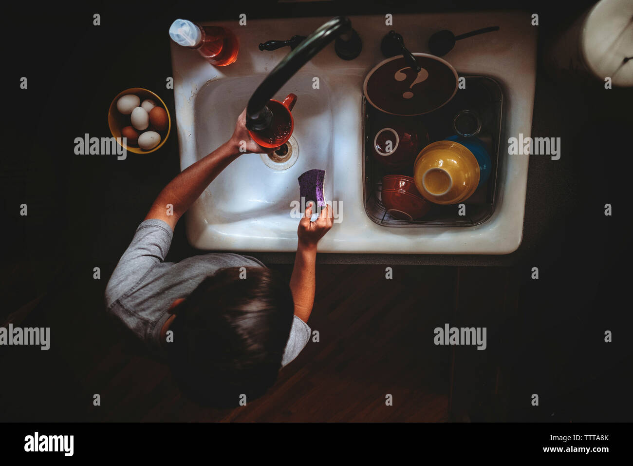 High angle view of teenage boy cleaning utensils in kitchen sink at home Stock Photo