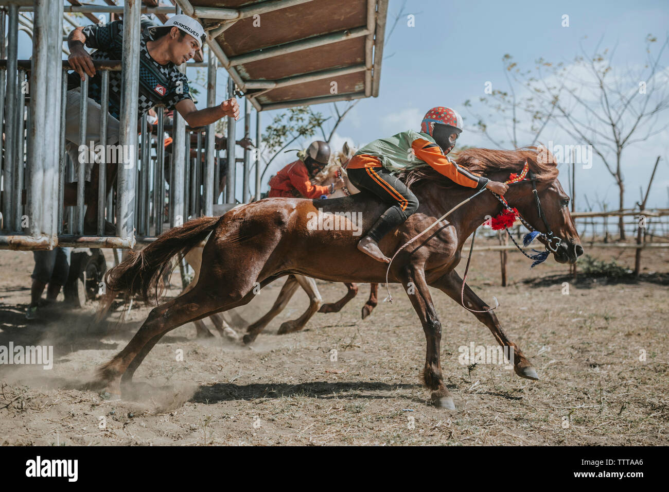 Child jockeys on racehorses at starting gate during horse racing Stock Photo