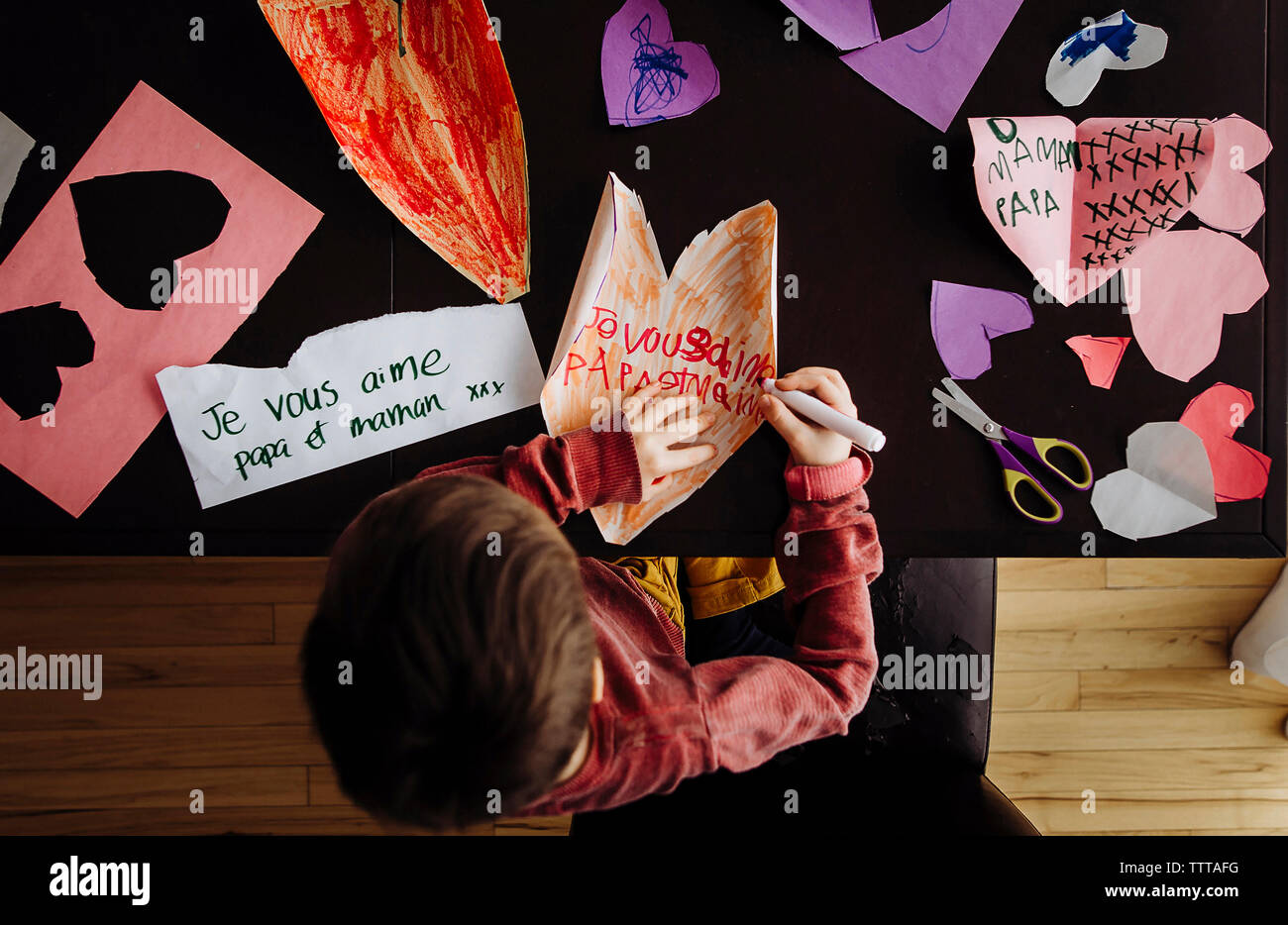 High angle view of boy writing on colorful papers at table Stock Photo