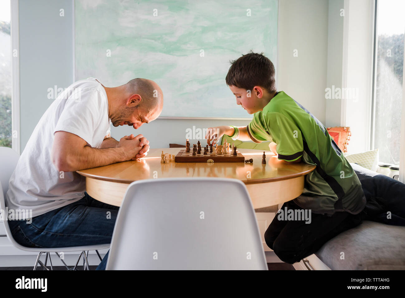 Father with son playing chess on table at home Stock Photo