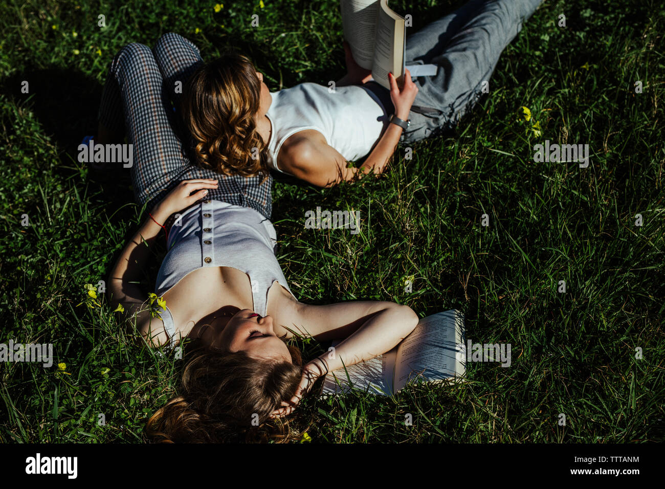 two young girls lying in the field read a book Stock Photo