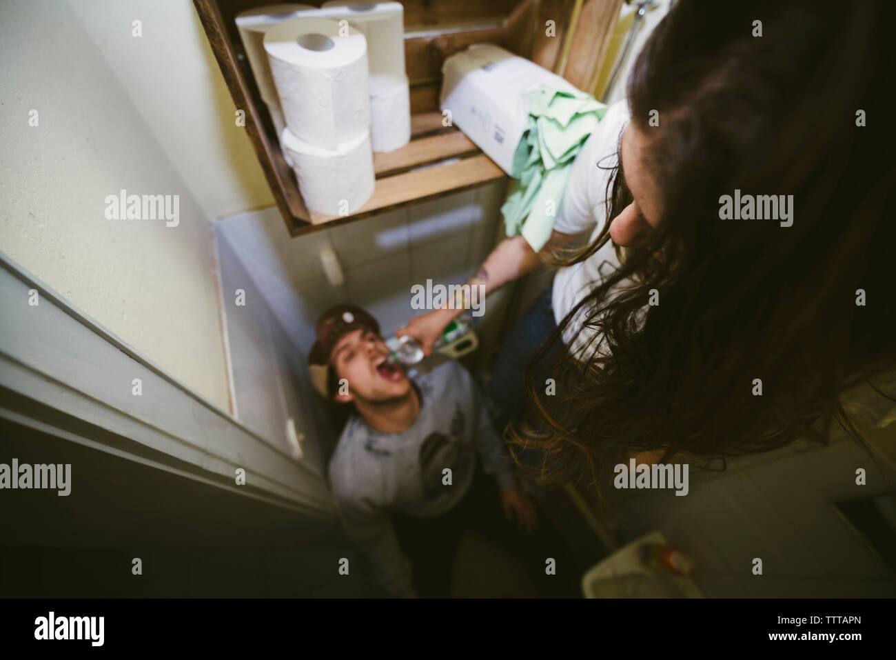 High angle view of woman feeding drinking water to man in bathroom Stock Photo