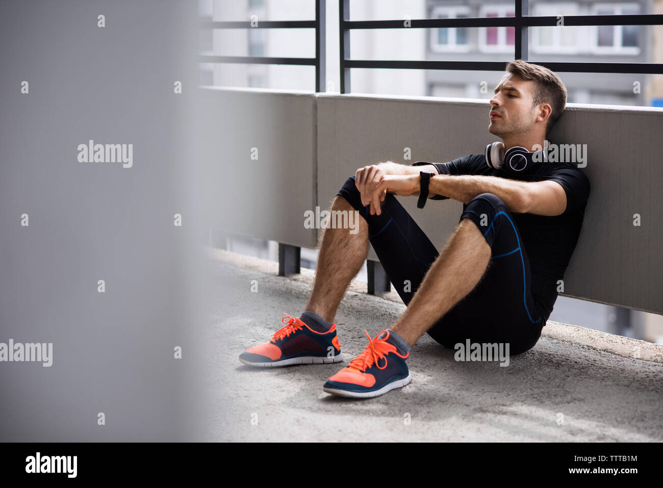 Tired male athlete sitting at parking lot Stock Photo