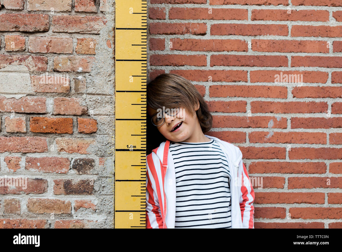Child In striped top Being Measured On A Keepsake Measuring Stick Stock Photo