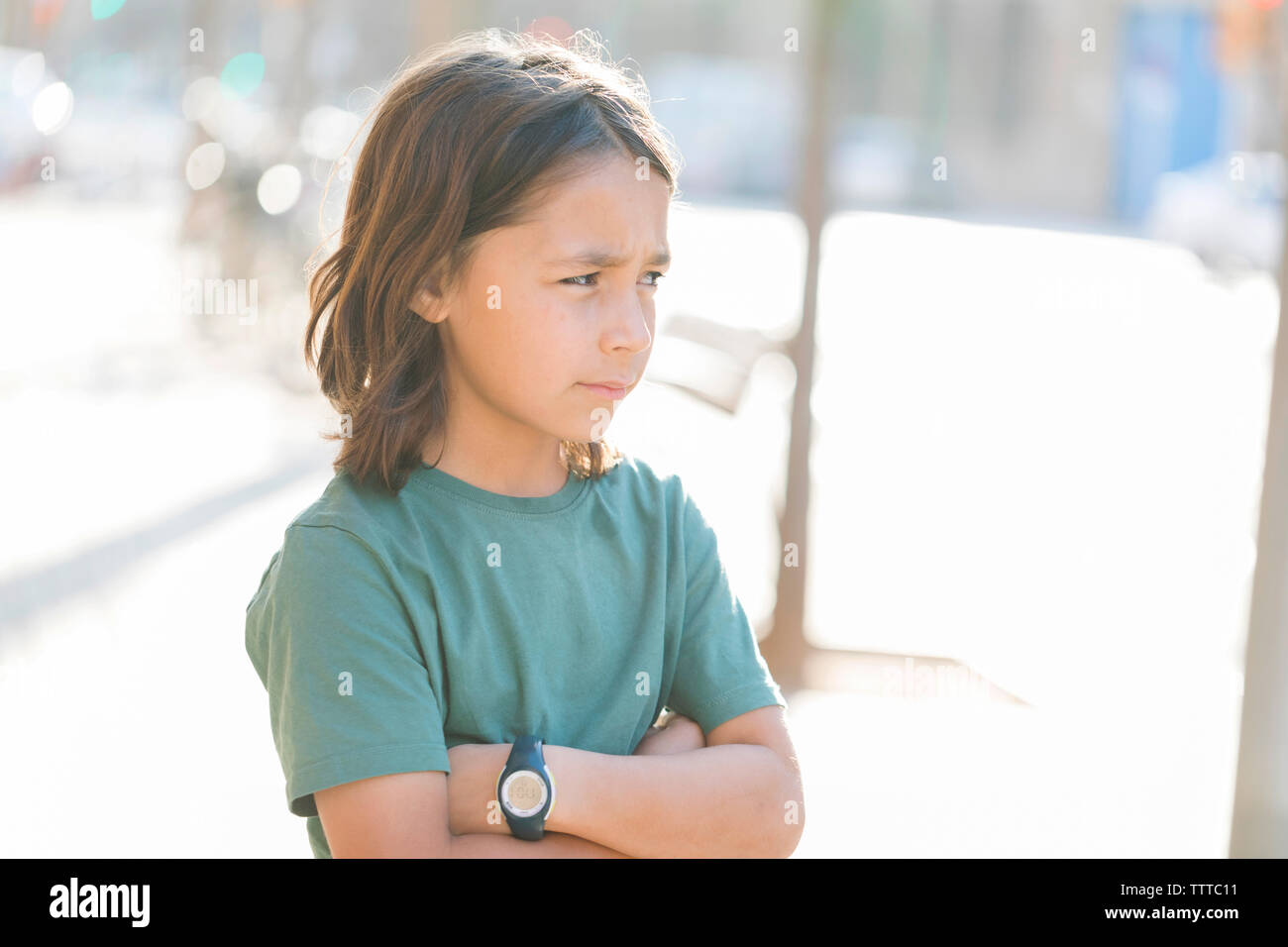 Crossed arms young long hair  boy on the sidewalk Stock Photo