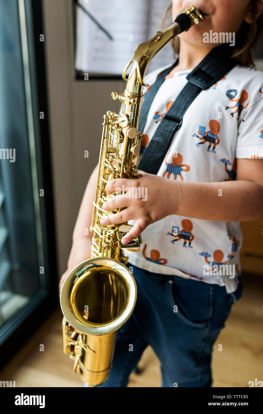 Faceless young boy playing saxophone on at home Stock Photo