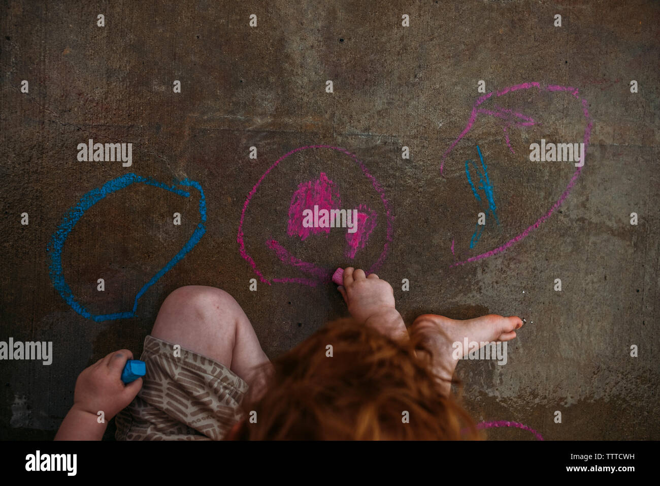 kid drawing with chalk on concrete Stock Photo Alamy