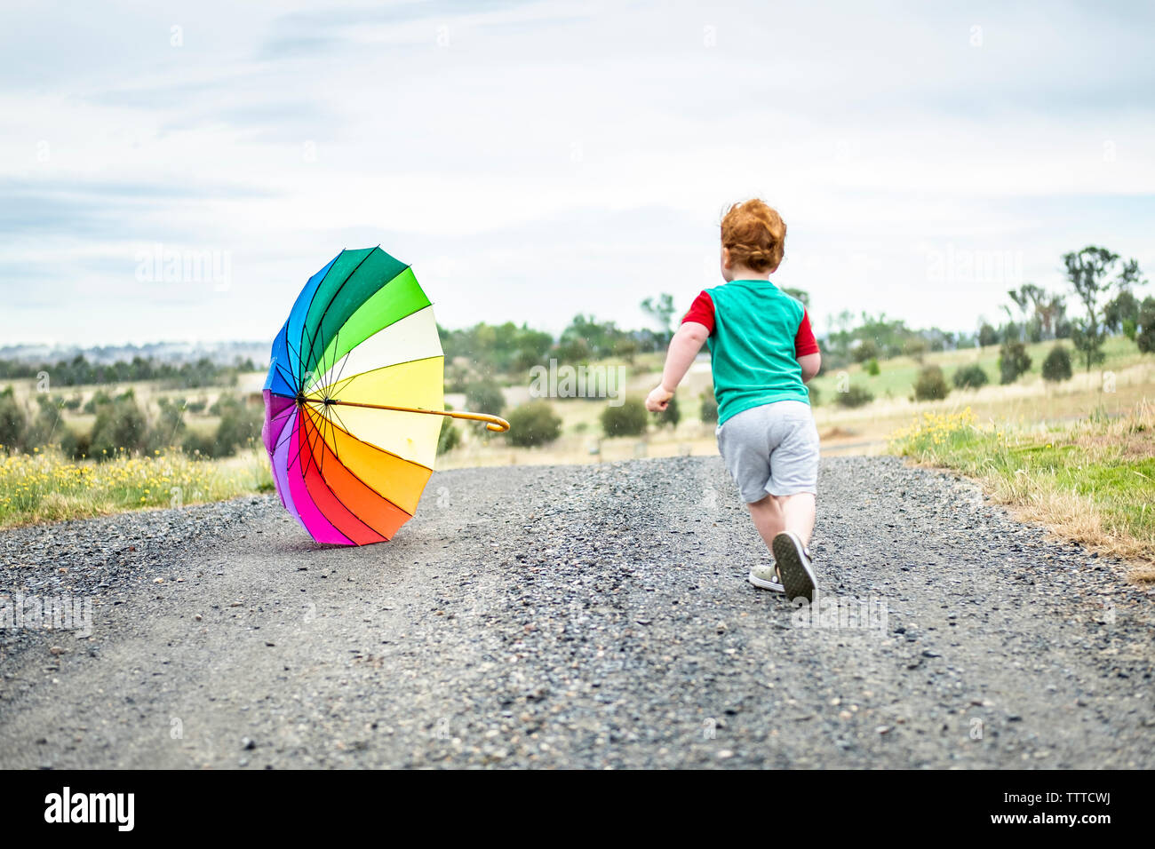 young boy chasing a rainbow umbrella Stock Photo