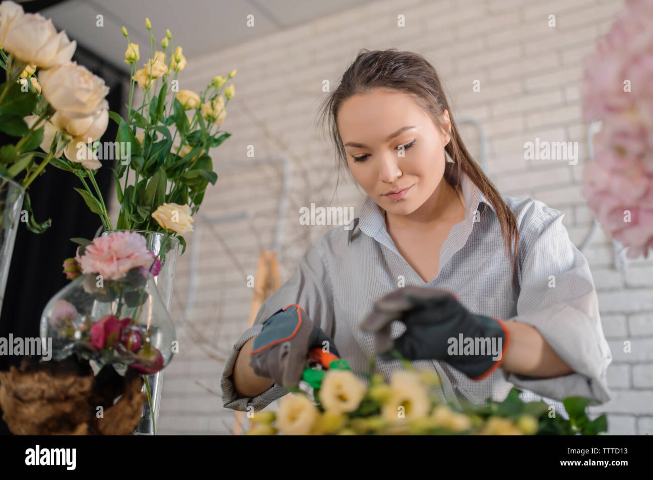 Female florist cutting flower while working in flower shop Stock Photo