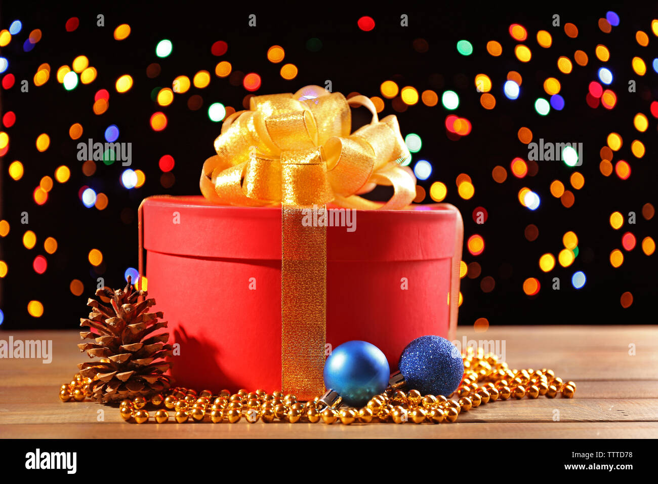 Red gift box with golden bow on colourful lights background Stock Photo ...
