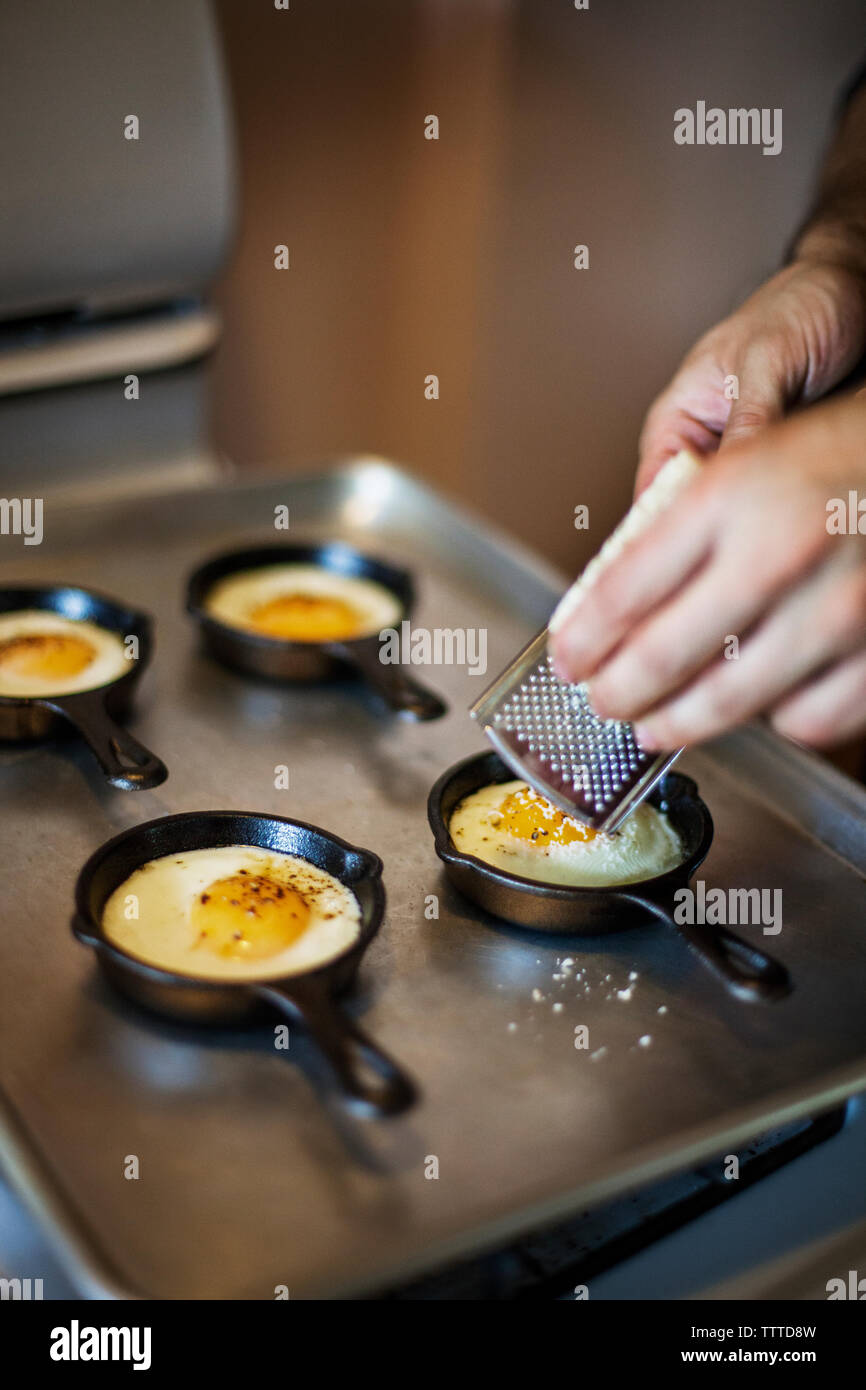 Man grating cheese on half fried eggs on baking sheet Stock Photo Alamy