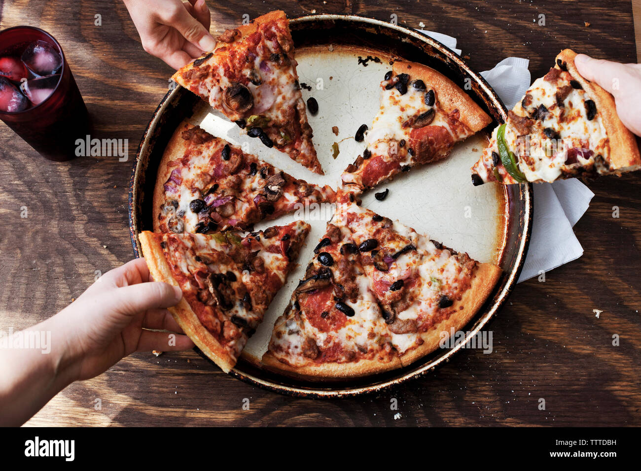 Overhead view of people eating pizza at wooden table Stock Photo