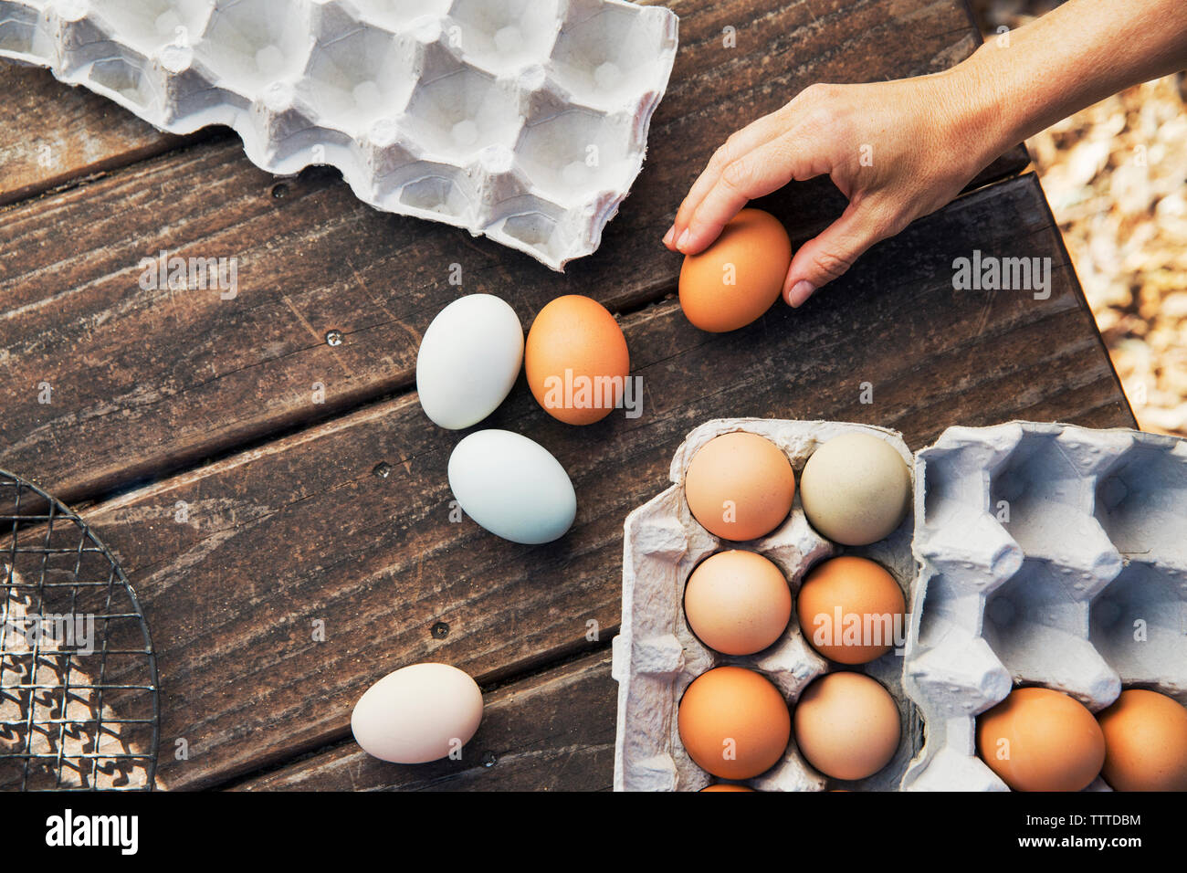 Overhead view of woman holding brown egg at wooden table Stock Photo