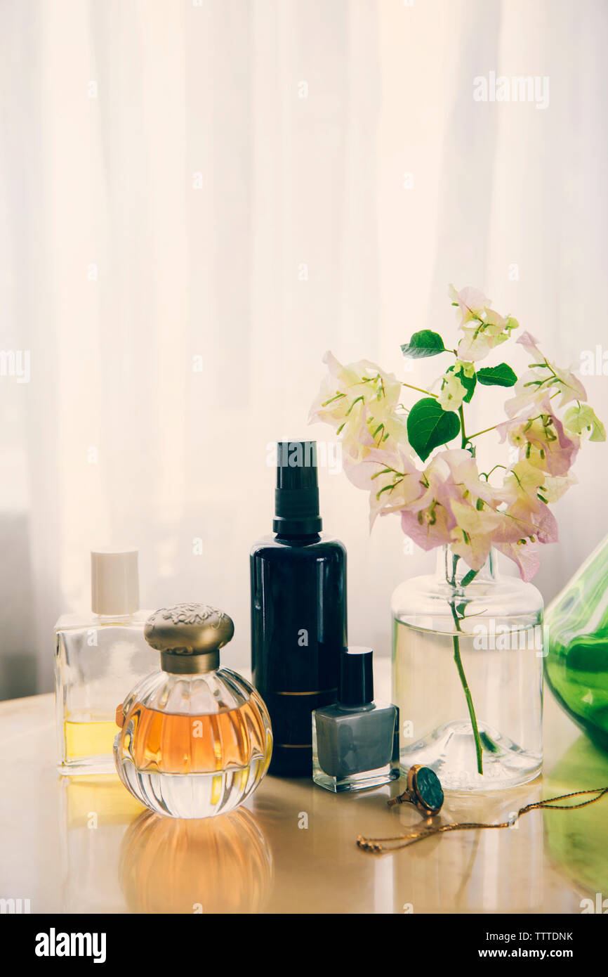 Beauty products with jewelry by flower vase arranged on table Stock Photo