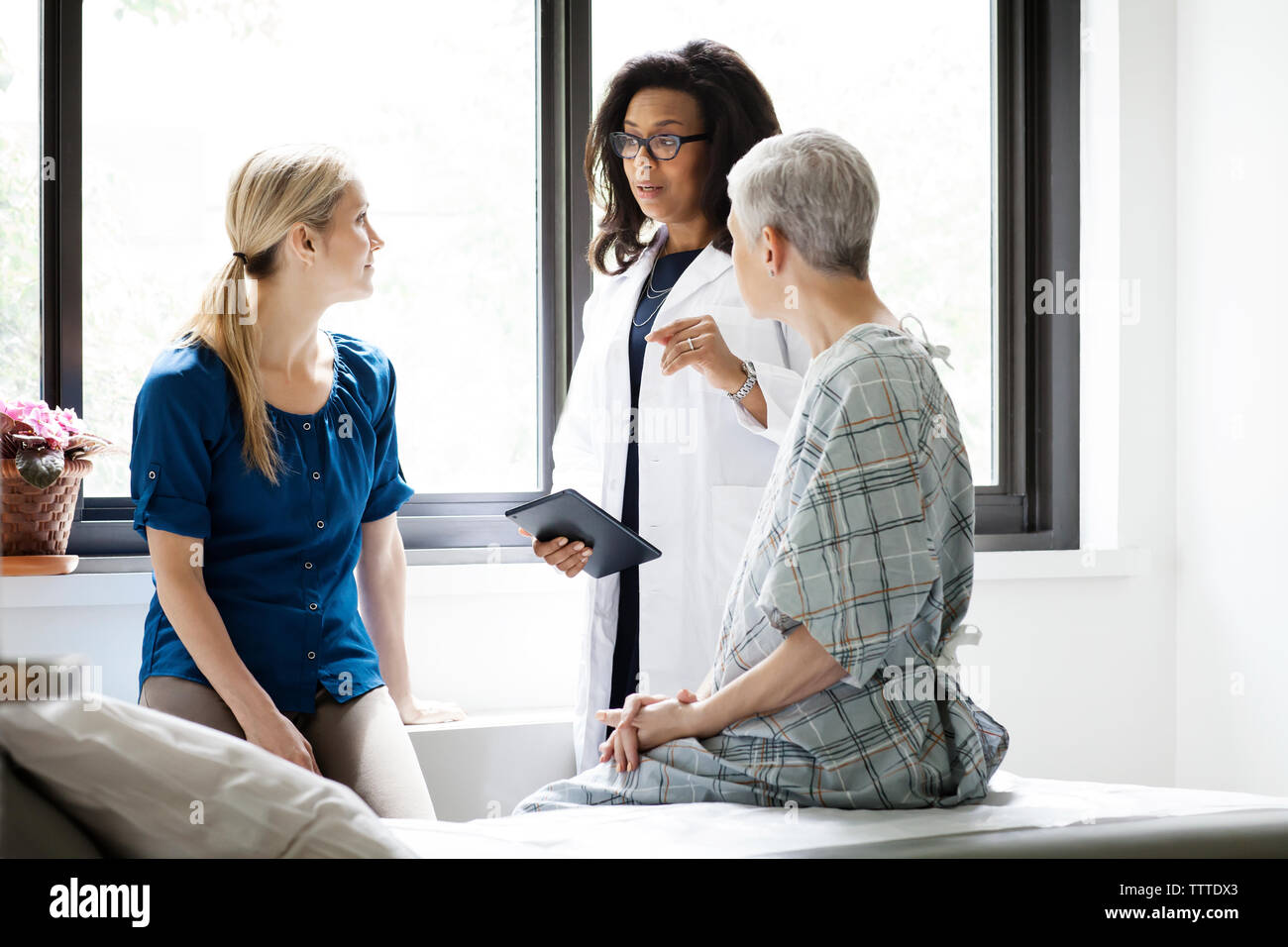 Doctor having discussing with woman and mature female patient in hospital Stock Photo