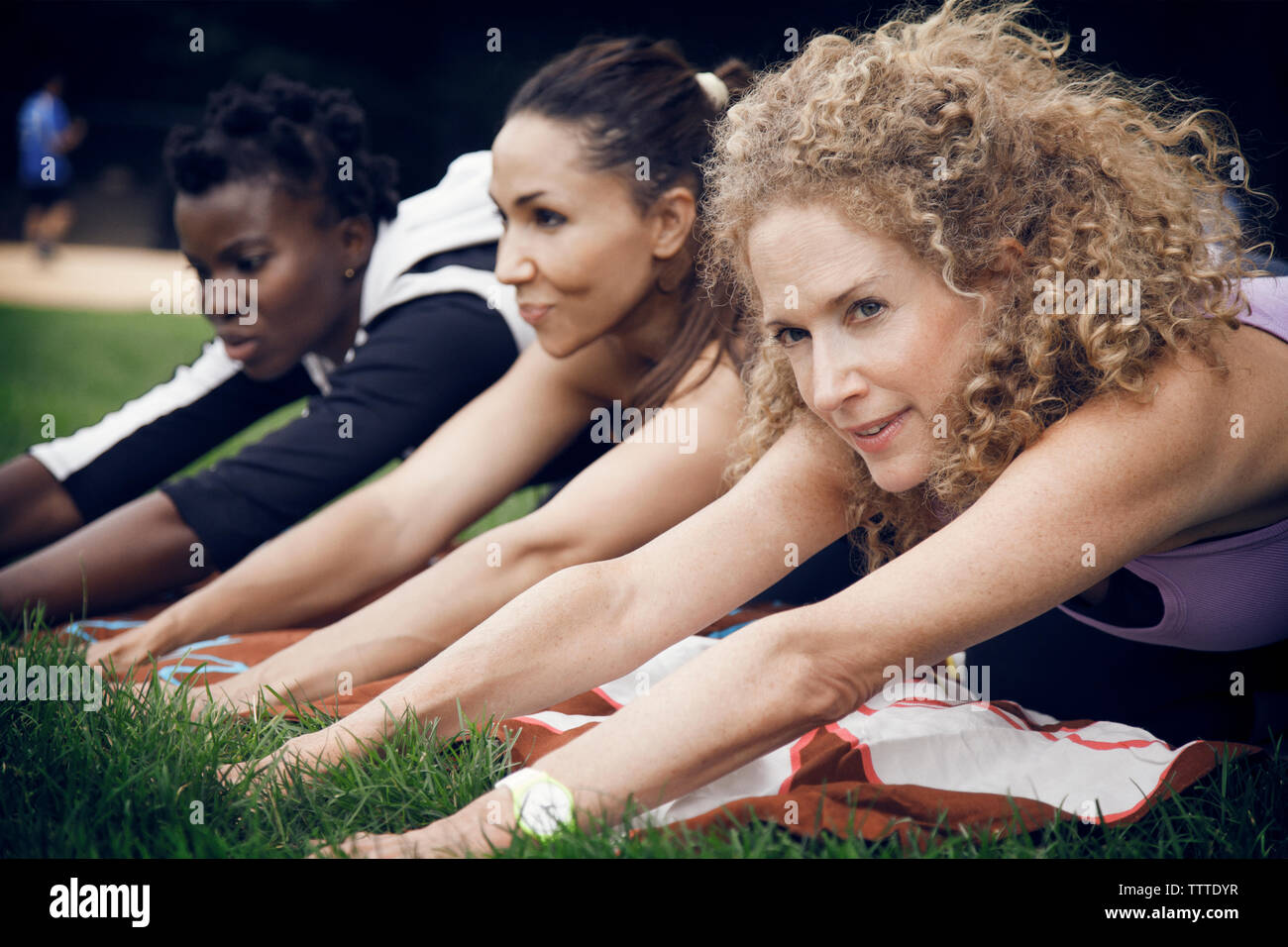 Determined athletes exercising on field at park Stock Photo