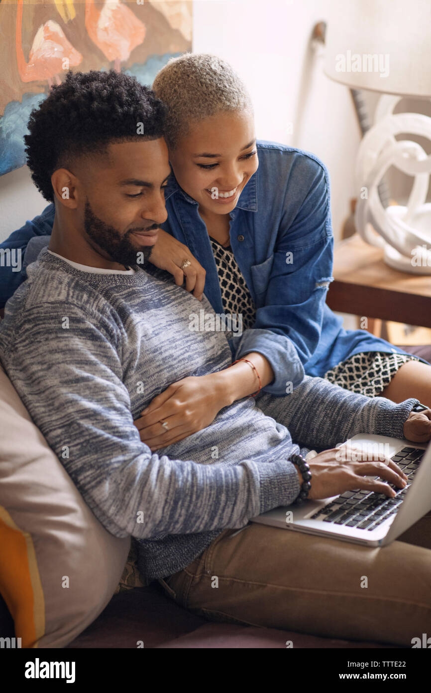 Couple using laptop computer while sitting on bed at home Stock Photo