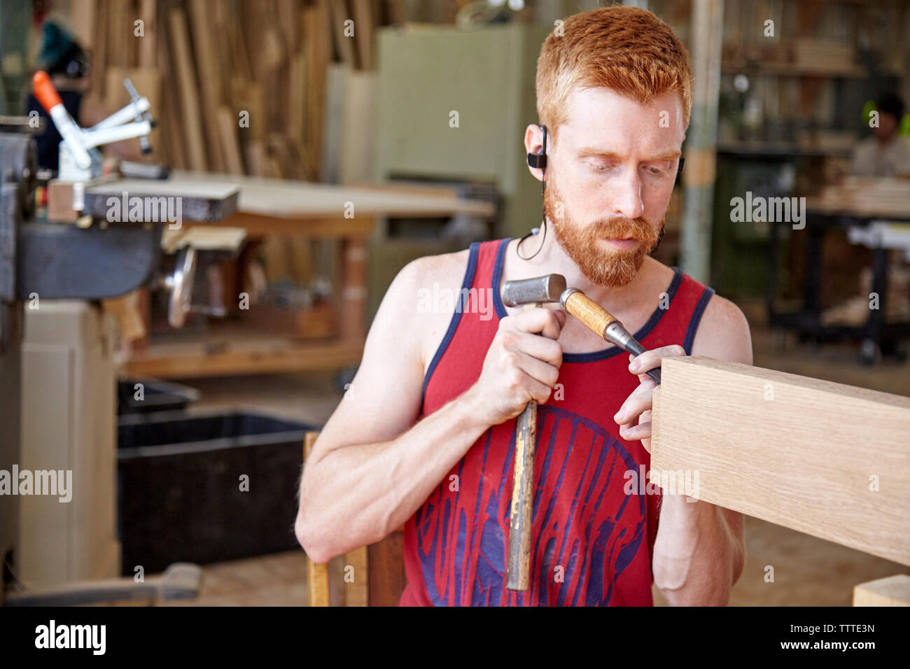 Craftsperson wearing earphones while working in workshop Stock Photo