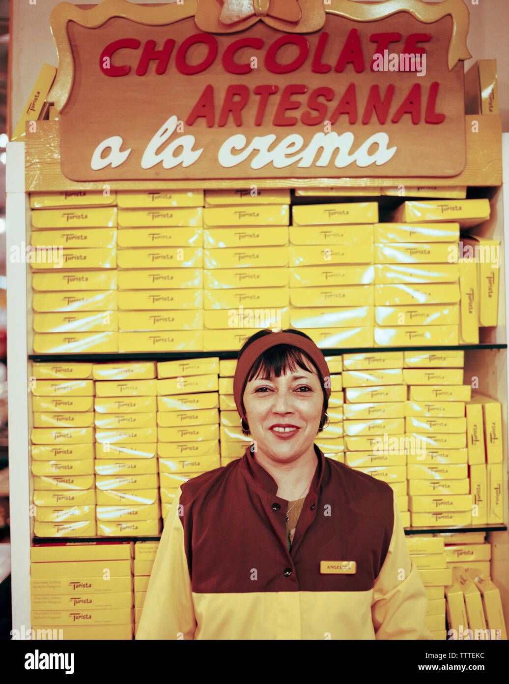 ARGENTINA, Bariloche, smiling lady with stack of packed chocolates at