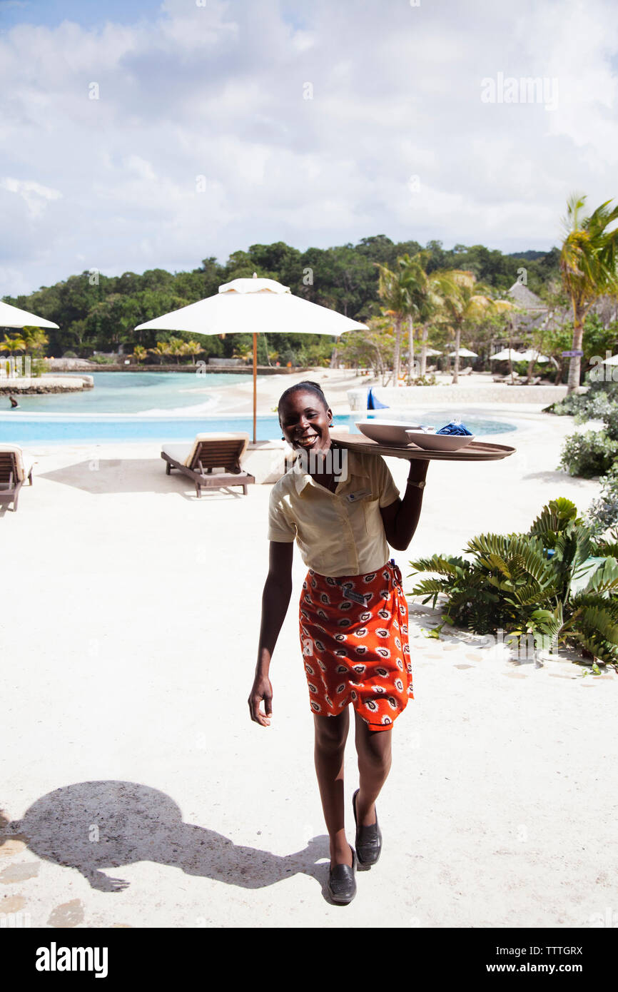 JAMAICA, Oracabessa. Goldeneye Hotel and Resort. Staff with tray of food at the pool area Stock