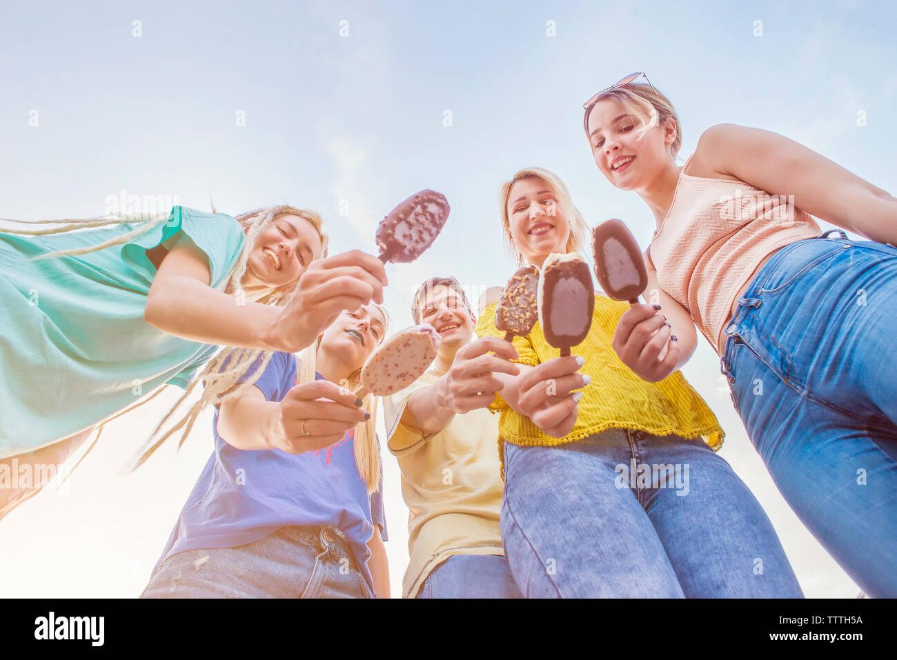 Group of young friends enjoying ice cream in the summer, view from below Stock Photo