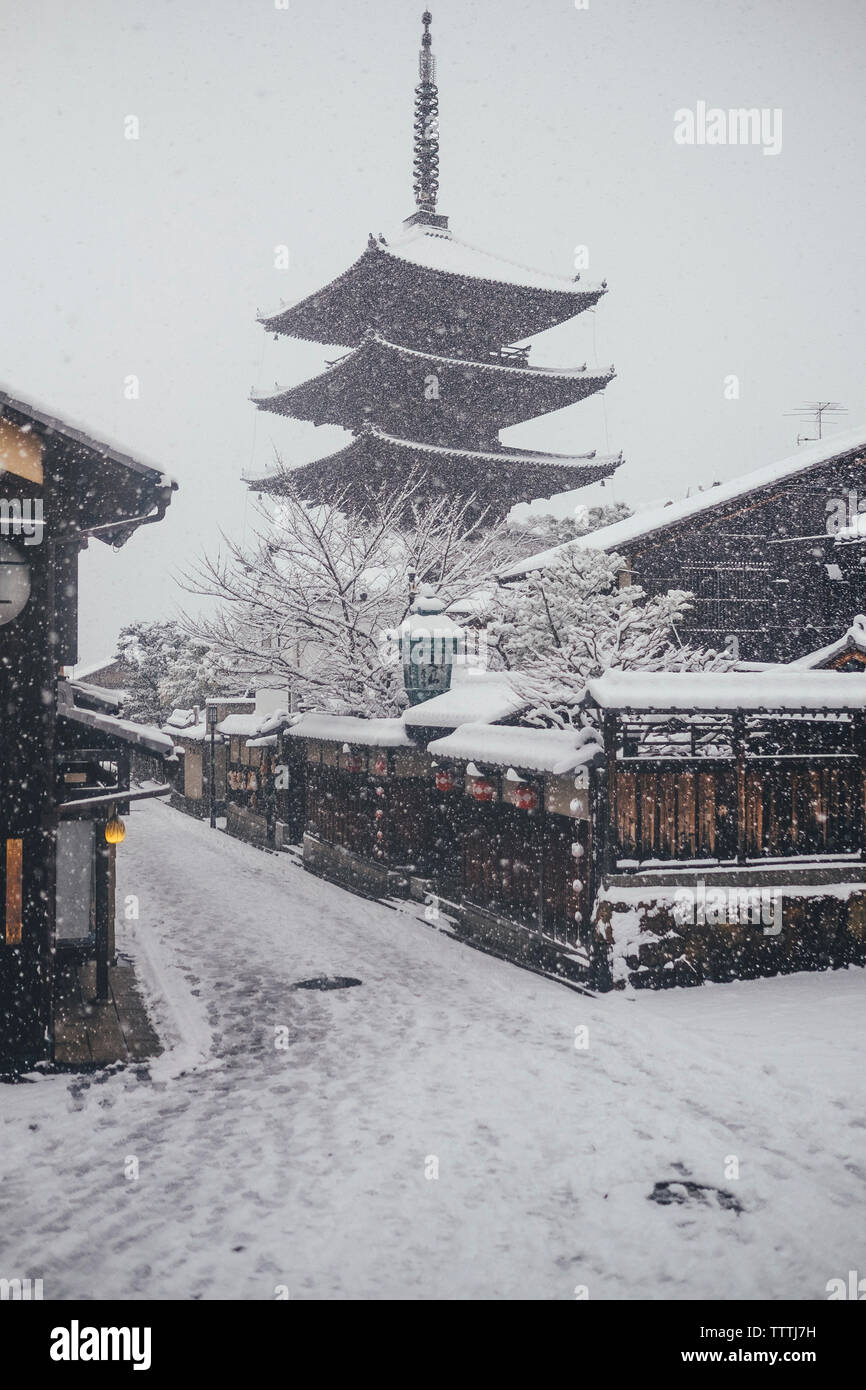 Low angle view of pagoda against clear sky during snowfall Stock Photo