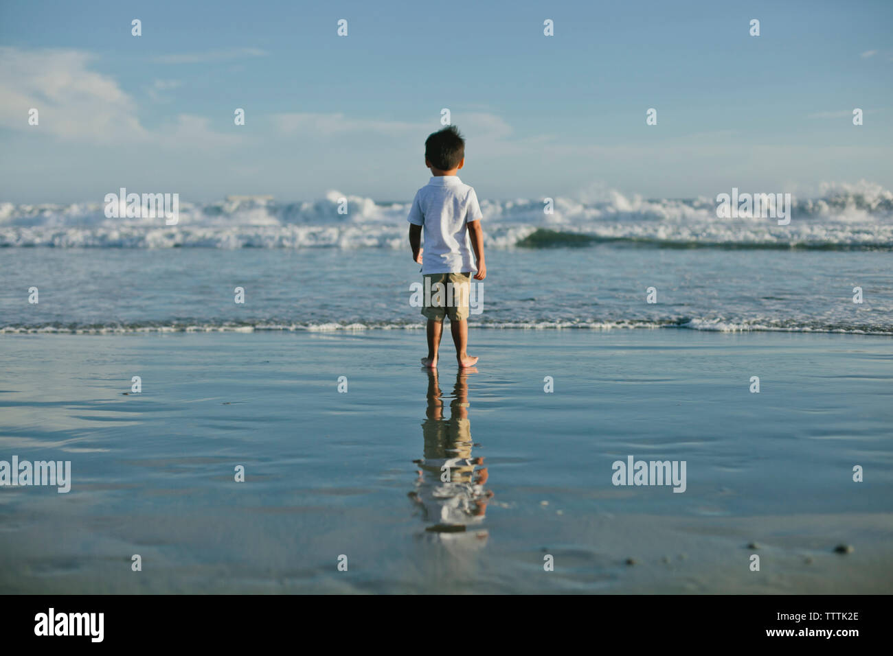 Rear view of boy standing at beach Stock Photo