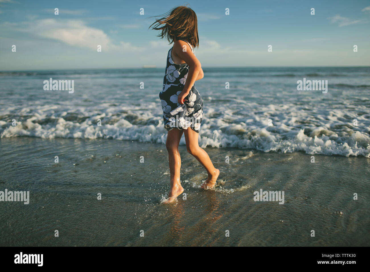 Playful girl running in sea during sunset Stock Photo