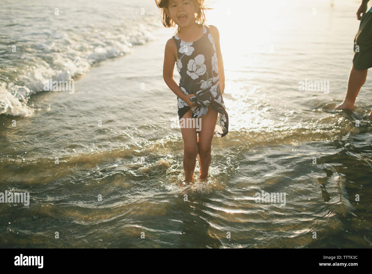 Girl playing in sea during sunset Stock Photo